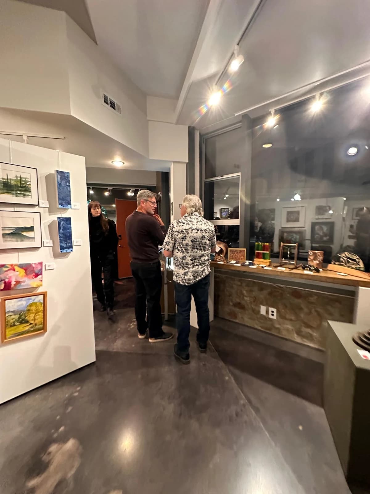 Visitors conversing among paintings at the Petit Masterpiece opening