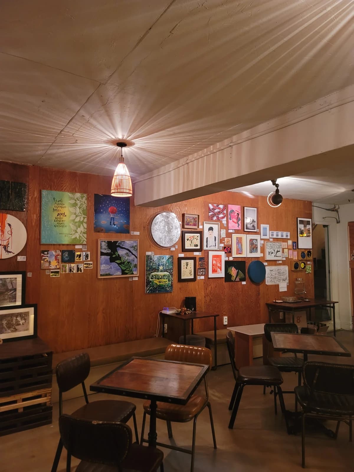 Paintings displayed around a wood-paneled exhibition room at Hechyeomoyeo 12