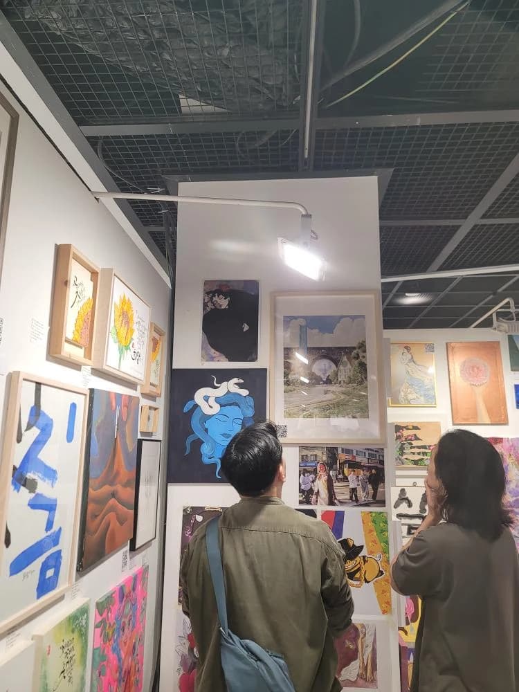 Two visitors viewing art beneath an open ceiling at IM INSA