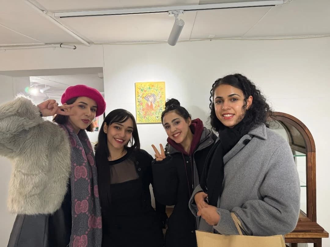 Four visitors posing together inside the Light That Remains exhibition