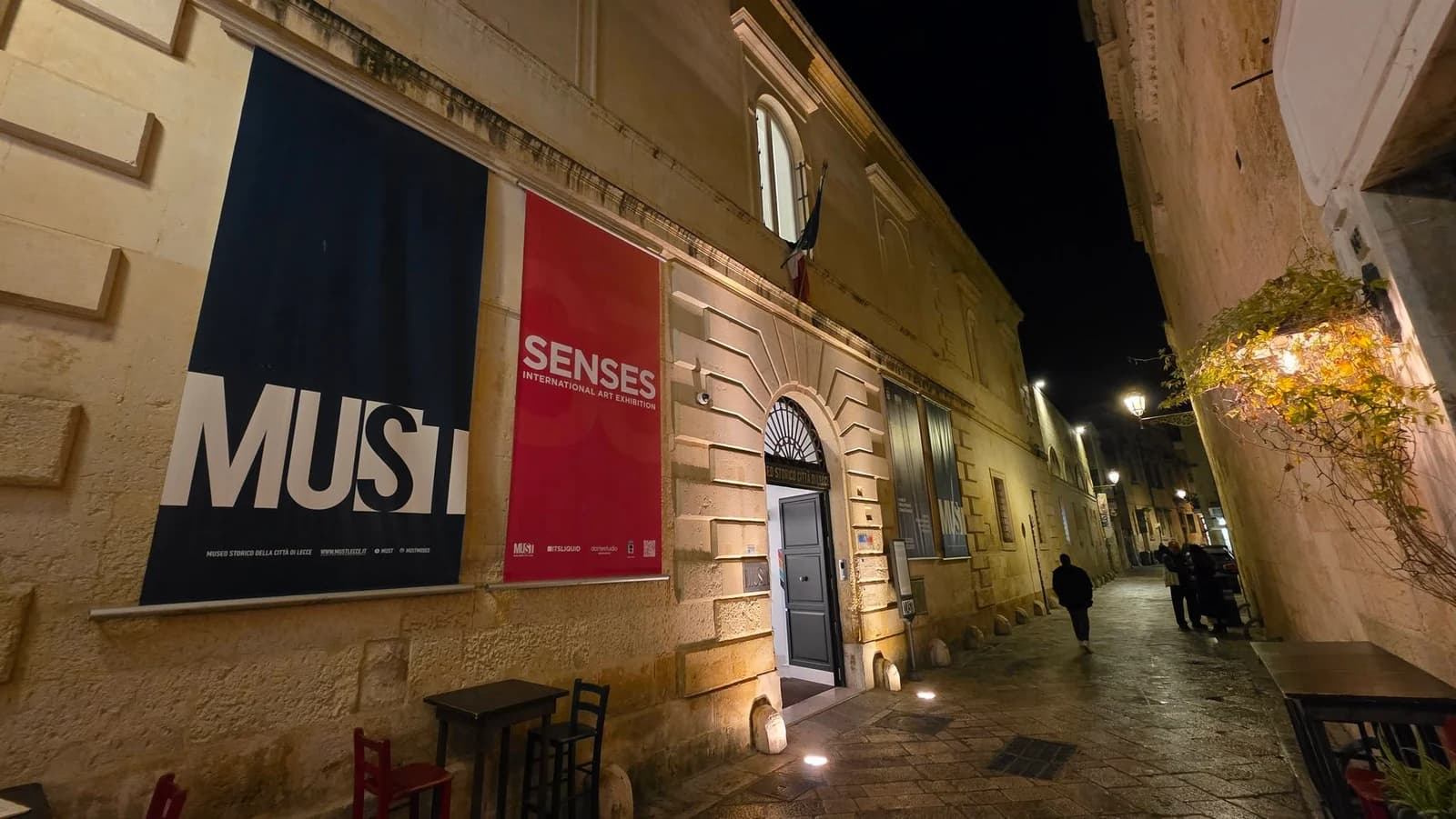 The illuminated MUST Museum exterior with a red Senses banner at night