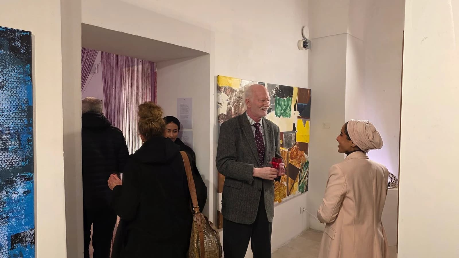 Visitors talking beside paintings inside the Senses International Art Fair venue