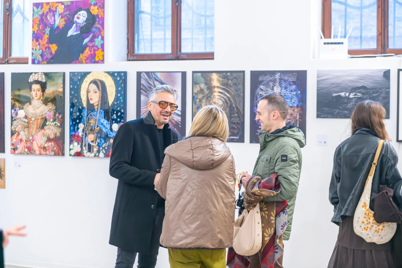 Visitors talking beside paintings at Contemporary Venice
